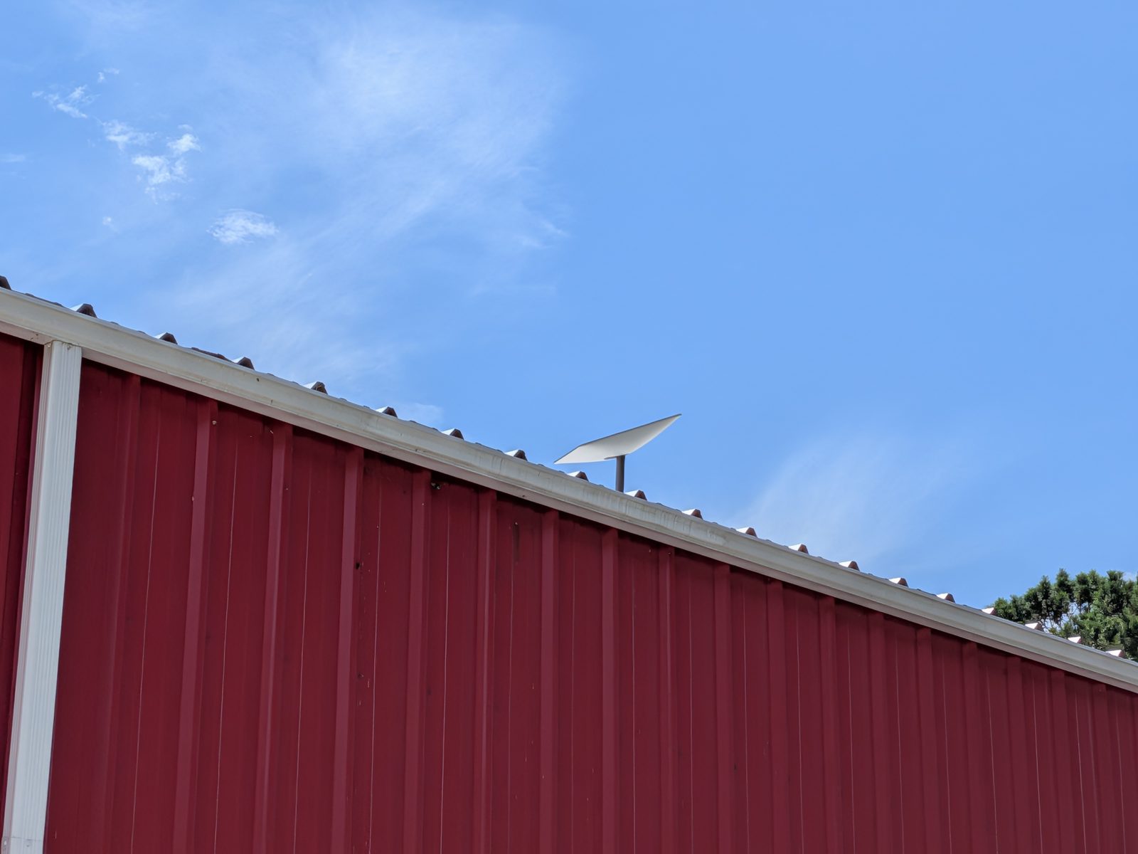 Starlink dish pole-mounted above a commercial roofline on the Outer Banks, clear sky view